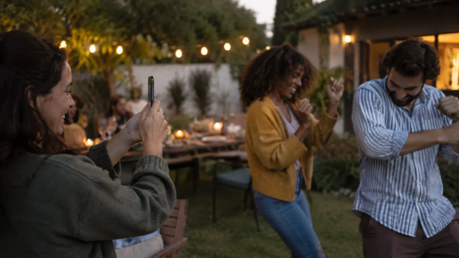 A guest recording two friends dancing at an informal garden party.